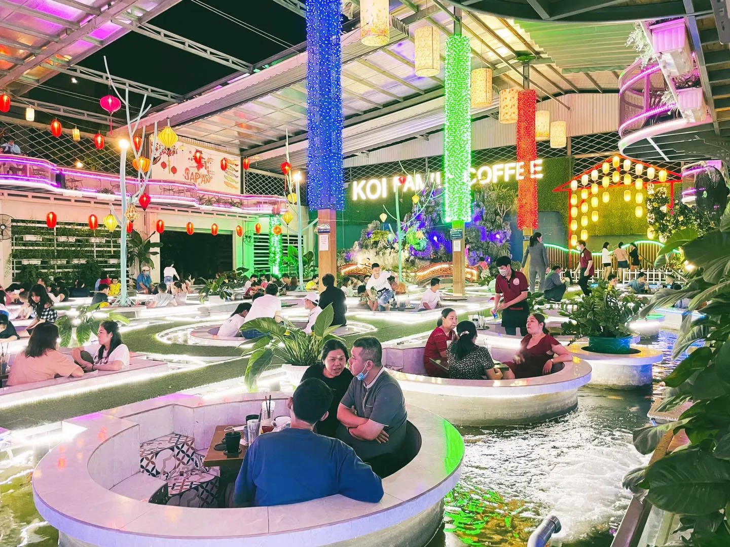 Khu vực bàn ghế riêng tư bao quanh hồ Koi tại Koi Family Coffee